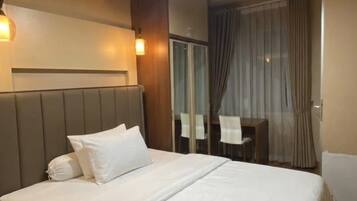 Une chambre d’hôtel avec un grand lit, des tables de chevet, un bureau et une vue sur l’extérieur.