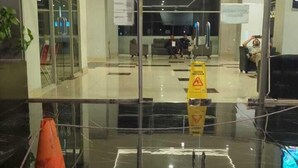 Eine moderne Lobby mit Glastüren, einem Schild wegen nasser Böden und einem Bauplakat.
