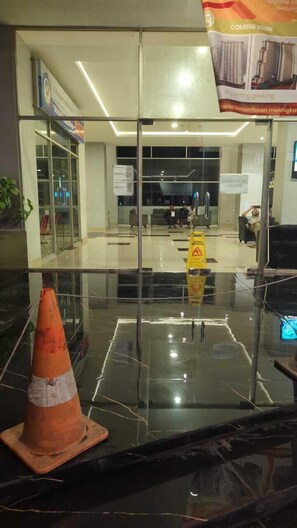 Un vestíbulo moderno con puertas de vidrio, un letrero de piso mojado y un cartel de construcción.