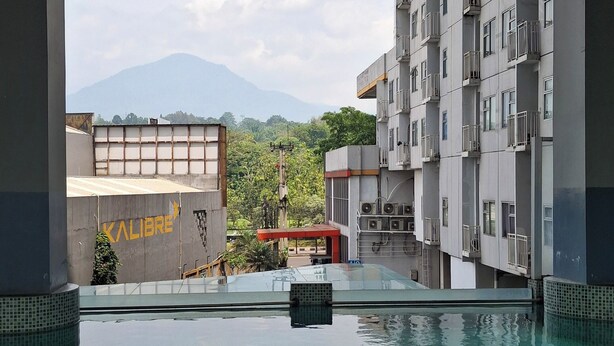 Ein Schwimmbad mit Blick auf ein Gebäude mit der Aufschrift 'KALIBRE' und einen Berg im Hintergrund.
