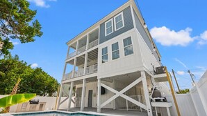 A two-story house with a balcony, a pool, and a garage. - Spacious NEW Luxury 5 Bedroom / 6 Bath Custom Home with Pool and Elevator (North Myrtle Beach)