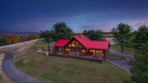 A lodge with a red roof, wooden deck, and a view of the surrounding landscape. - Whether you`re looking for a romantic getaway or a fun-filled family vacation, this cabin is the perfect destination for you. (Herndon)