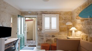 Una stanza accogliente con una parete in pietra, una scrivania in legno, una televisione, un divano e una lampada.