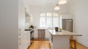 Una cucina moderna con mobili bianchi, elettrodomestici in acciaio inossidabile e pavimento in legno.