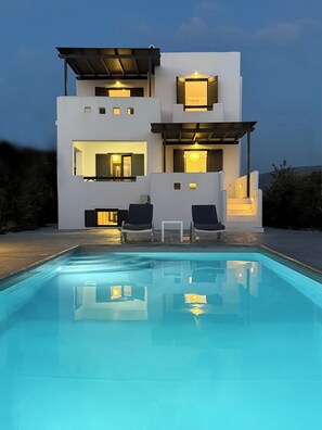 Una casa moderna de dos pisos con una piscina al frente.