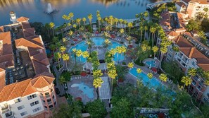An aerial view of a resort with multiple swimming pools, palm trees, and a waterfront. - Large 2 bedroom with full kitchen inbetweenDisney World and Universal Theme Park (Orlando)