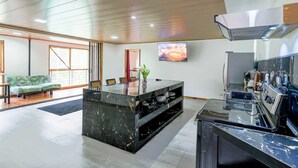 Een moderne keuken met een marmeren kookeiland, een zithoek met een bank en een groot raam.