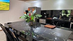 Een moderne keuken met een marmeren eiland, een koffieapparaat en een plant op het aanrecht.