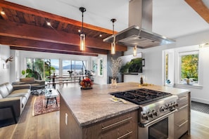 Una cocina moderna con una isla central, electrodomésticos de acero inoxidable y grandes ventanales con vistas al exterior.