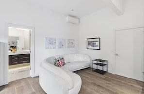 A modern living room with a white sofa, a black side table, and a framed picture on the wall. - Bayview Modern Luxury by the Lake (Bellevue)