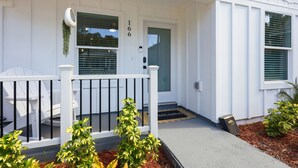 A white house with a number 166 on the door, a porch with white railings, and a small plant in the foreground. - Family Getaway: Pet Friendly • Close to Downtown (St. Augustine)