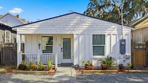 A single-story house with a white exterior, a front door, and a small porch with a railing. - Family Getaway: Pet Friendly • Close to Downtown (St. Augustine)