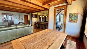 Un vaste espace de vie comprenant une table à manger en bois, un canapé en cuir et une cuisine à l’arrière-plan.