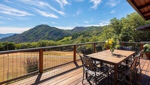 Une terrasse en bois avec une table et des chaises, offrant une vue sur un paysage montagneux.