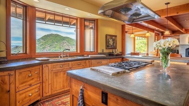 Une cuisine avec des meubles en bois, un grand îlot central et une vue sur une montagne.