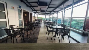 A corridor with tables and chairs, large windows, and a fire extinguisher. - HOTEL SAN ANTONIO PLAZA APARTADO (Apartadó)