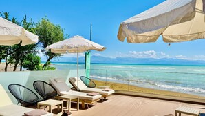 Eine Strandlounge mit Liegestühlen, Sonnenschirmen und Blick auf das Meer.
