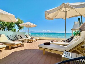 A beachside lounge area with sunbeds, umbrellas, and a view of the ocean. - Beachfront Villa Anatoli with private heated pool (Sidari)