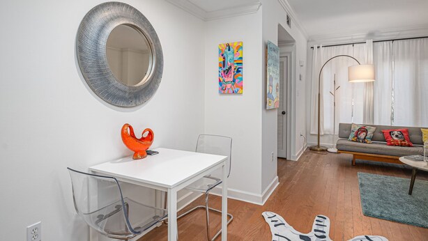 Uma sala de estar moderna com um sofá branco, obras de arte coloridas e um espelho redondo na parede.