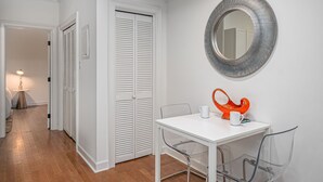 Um quarto claro com uma mesa, cadeiras, um espelho e uma porta com venezianas.
