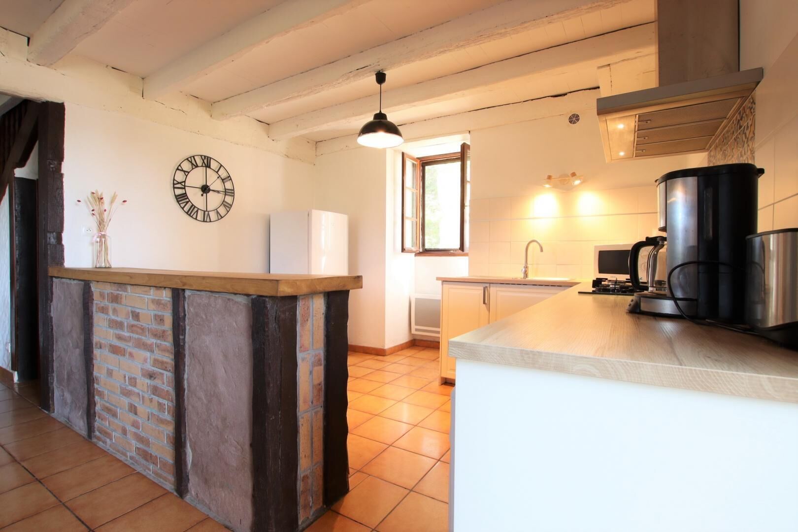 A kitchen with a central island, a clock, and a window.