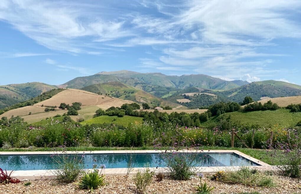 A pool with a view of rolling hills and mountains in the background.