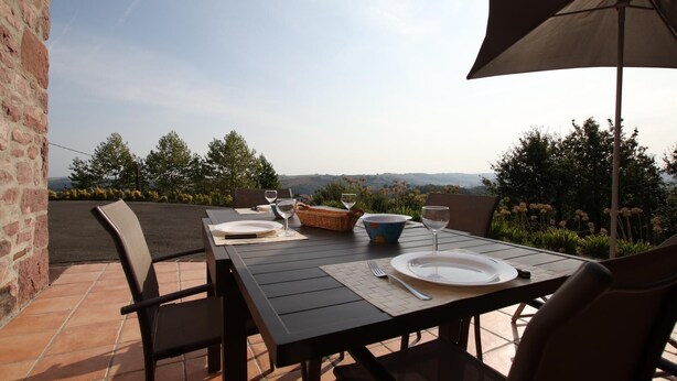Un área de comedor al aire libre con una mesa preparada para dos, una cesta de mimbre y un tazón.