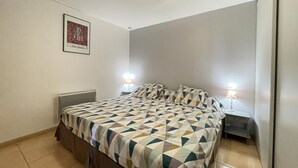 Un dormitorio con una cama, dos lámparas de noche, un radiador y un cuadro en la pared.