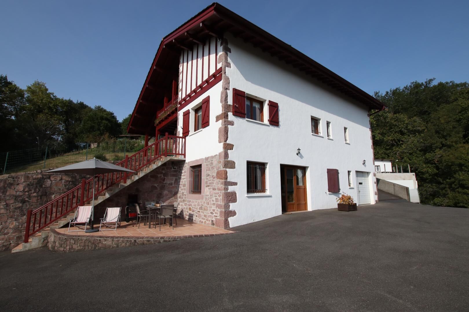 A two-story building with a stone facade, red accents, and a staircase leading to a balcony.