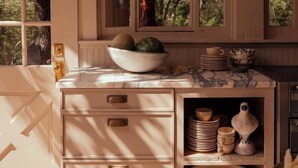 Una cocina con armarios de madera, encimera de mármol y ventana con vistas a árboles.