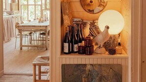 Una habitación acogedora con una mesa de madera, una estantería con botellas de vino, una escultura de pájaro y un cuadro.