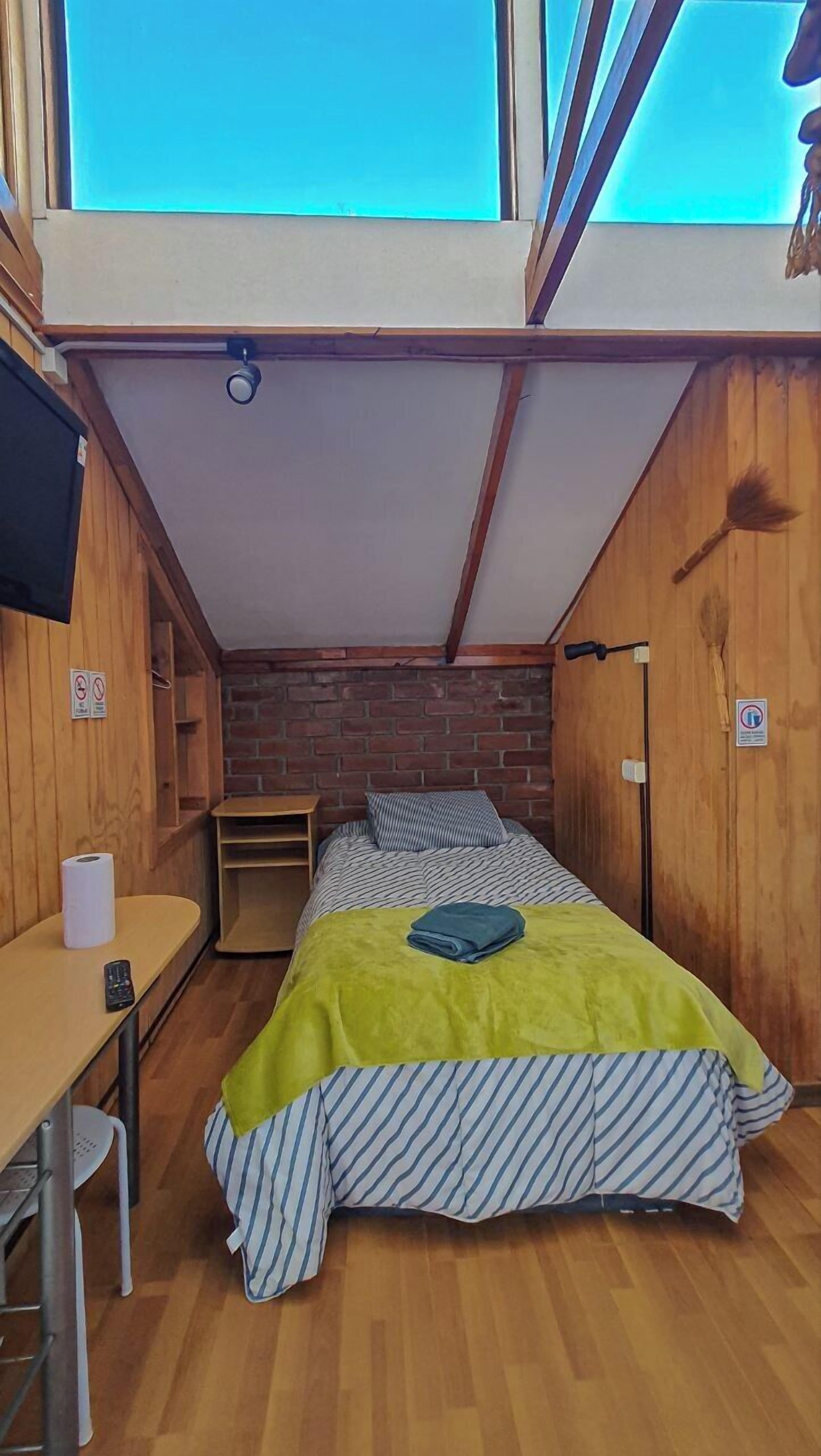 A compact room with a bed, a small table, and a TV.