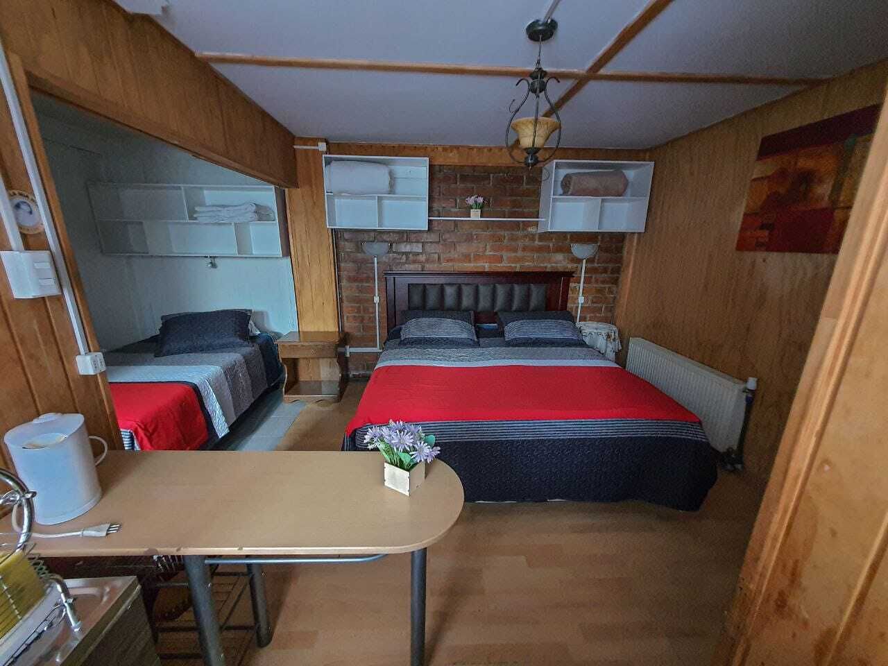 A compact room with two beds, a small table, and a radiator.