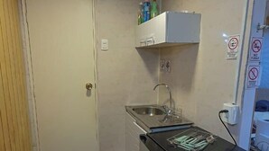 Una cocina compacta con un lavabo, un refrigerador pequeño y piso de madera.