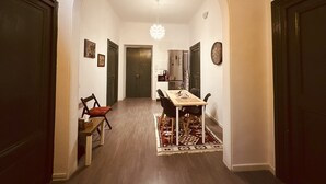 A hallway leading to a dining area with a table and chairs, a chandelier, and a patterned rug. - Caserina Lux Roma (Rome)