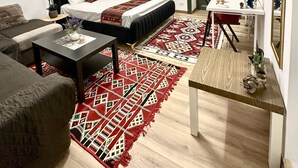 A modern bedroom with a bed, a sofa, a coffee table, a TV, and a dining area with a table and chairs. - Caserina Lux Roma (Rome)