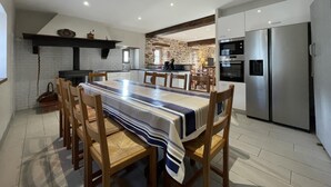 A modern kitchen with a large island, built-in appliances, and a dining area with a striped tablecloth. - MARTIN AUNDIENIA - SARE (SARE)