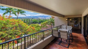 Ein Balkon mit Blick auf eine üppige Landschaft, einschließlich Palmen und einem entfernten Gebirgszug.