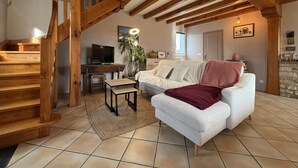 Ein geräumiger Wohnbereich mit einer Holztreppe, einem Sofa, einem Couchtisch und einem Fernseher.