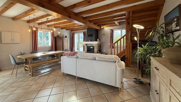Eine geräumige K üche mit Holzbalken, einem Essbereich mit einer Bank und einem Sofa.