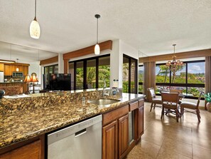 A spacious kitchen with granite countertops, a dishwasher, wooden cabinets, and a large island. - Kaanapali Alii 254 | Hot tub | Pool | Garden Views (Lahaina)