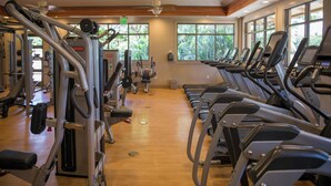Ein Fitnessraum mit Laufbändern, Kraftgeräten und einer Holzbalkendecke.