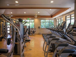 Ein Fitnessraum mit Laufbändern, Kraftgeräten und einer Holzbalkendecke.