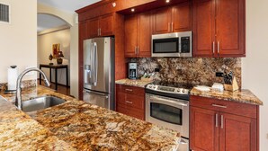 Eine moderne Küche mit Granit Arbeitsplatten, Edelstahlgeräten und Holzschränken.