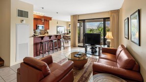 Ein modernes Hotelzimmer mit einer Küche, einem Wohnbereich mit Ledersofas, einem Flachbildfernseher und einem Balkon mit Aussicht.