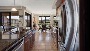 Eine moderne Küche mit Edelstahlkühlschrank, Granit Arbeitsplatten und einem Essbereich mit Blick.