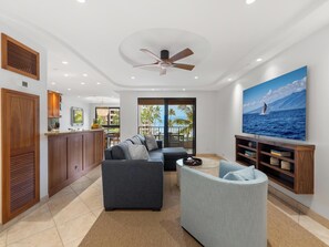 Ein modernes Wohnzimmer mit Sofa, Sesseln und einem großen Gemälde vom Meer.