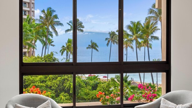 Una habitación con un ventanal que ofrece vistas a palmeras y a la playa.