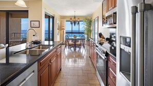 A modern kitchen with a view of the ocean, stainless steel appliances, and a dining area with a view. - Ocean Views from the Top Floor - Kaanapali Alii 4112 (Lahaina)