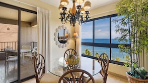 A balcony with a glass table, wicker chairs, a decorative mirror, and a potted plant. - Ocean Views from the Top Floor - Kaanapali Alii 4112 (Lahaina)